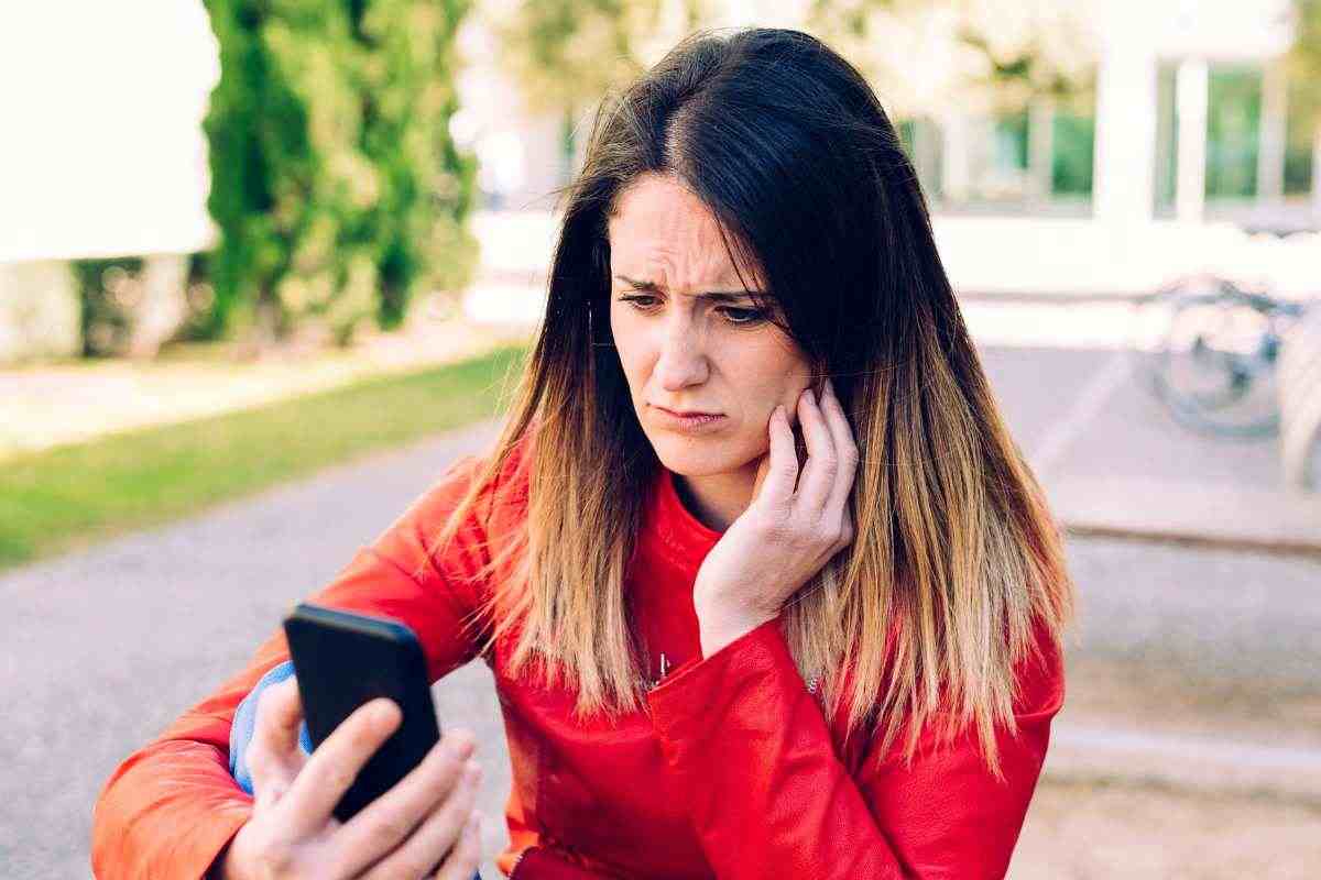 donna che guarda lo smartphone con preoccupazione